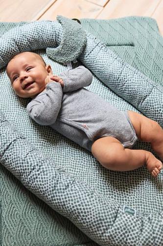 blije baby in babynestje Vol Verwachting - Blije baby die op een dekentje in een babynestje ligt